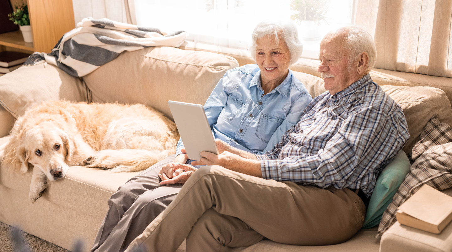 Senior en EHPAD utilisant une tablette pour un appel vidéo avec sa famille, sourire aux lèvres